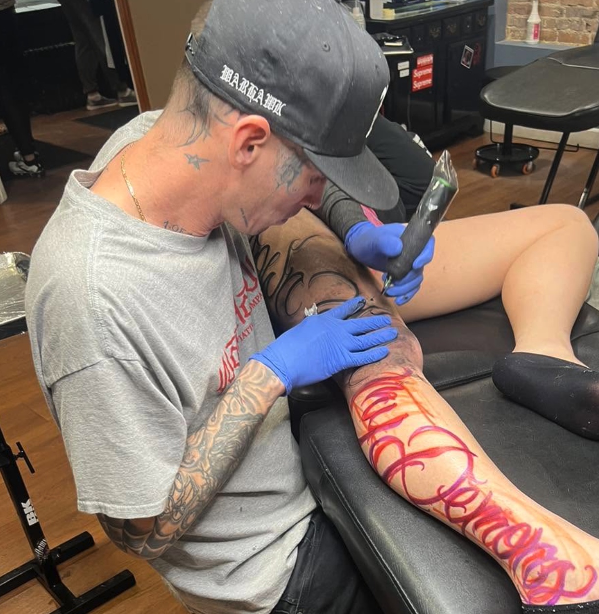 Brandon Kinser tattooing lettering on a client's leg at WarHawk Tattoo Company